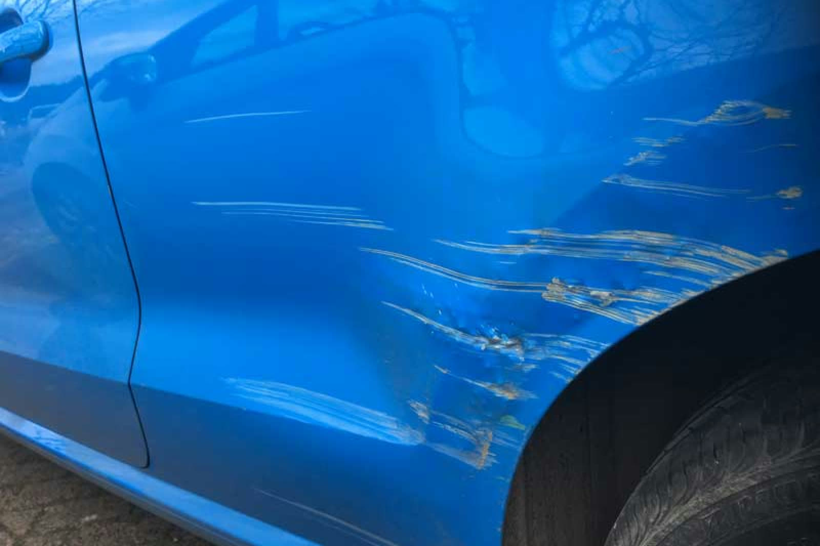 Deep scratches gouged through the paint on a blue car door